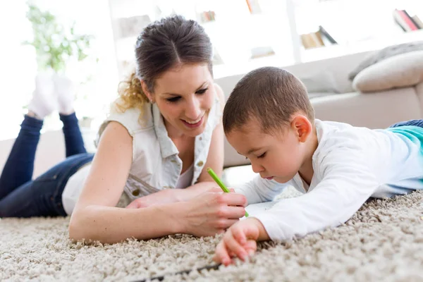 Bela jovem mãe e seu filho desenho em casa . — Fotografia de Stock