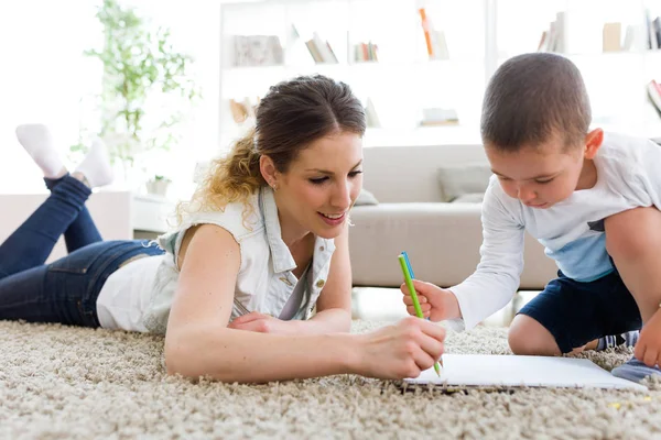 Bela jovem mãe e seu filho desenho em casa . — Fotografia de Stock