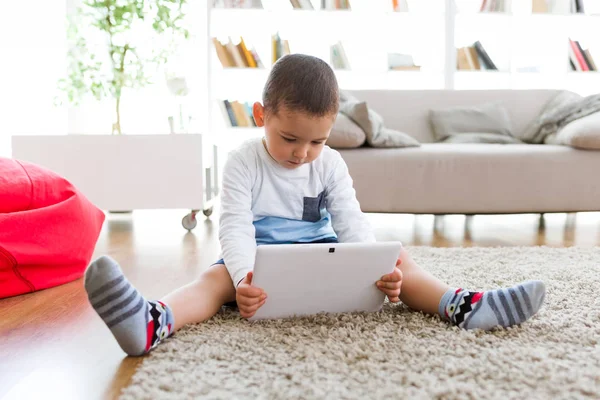 Vacker ung pojke med sin digitala surfplatta hemma. — Stockfoto