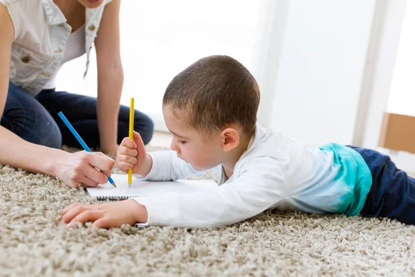 Beautiful young mother and her son drawing at home. — Stock Photo, Image