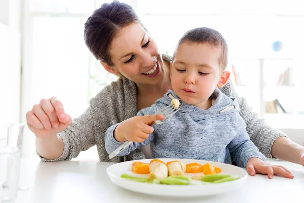美丽的年轻母亲和她的儿子在家里吃水果. — 图库照片