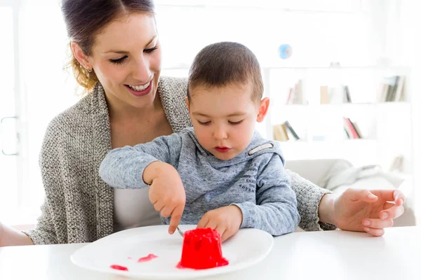 Schöne junge Mutter und ihr Sohn essen Erdbeergelee bei ho — Stockfoto