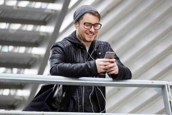 Moderne jonge man met zijn mobiele telefoon in de straat. — Stockfoto