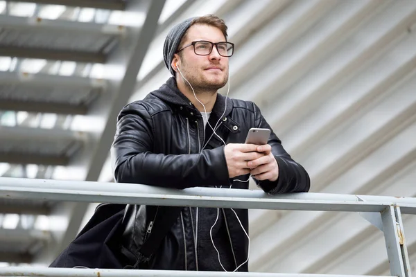 Moderner junger Mann hört Musik mit Handy auf der Straße. — Stockfoto