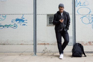 Modern genç adam sokakta cep telefonunuzla müzik dinlemek.
