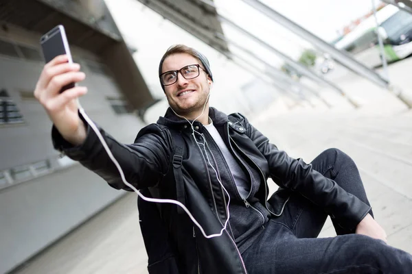 Jovem moderno tirando uma selfie com telefone celular na rua — Fotografia de Stock