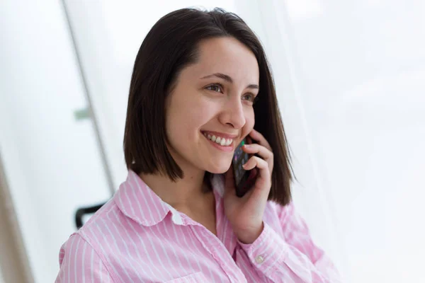 Belle jeune femme utilisant son téléphone portable dans le bureau . — Photo