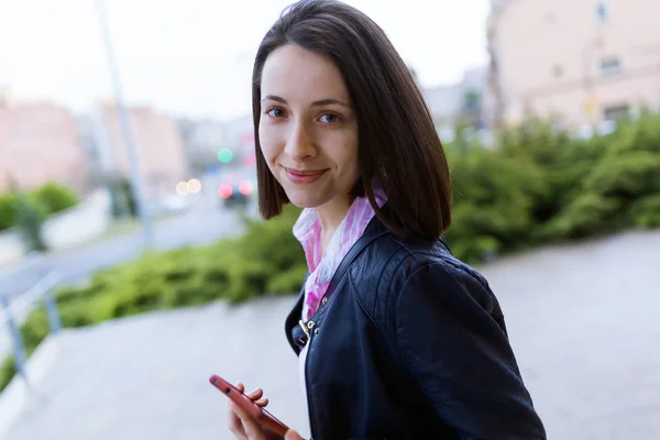 Bella giovane donna che utilizza il suo telefono cellulare in strada . — Foto Stock