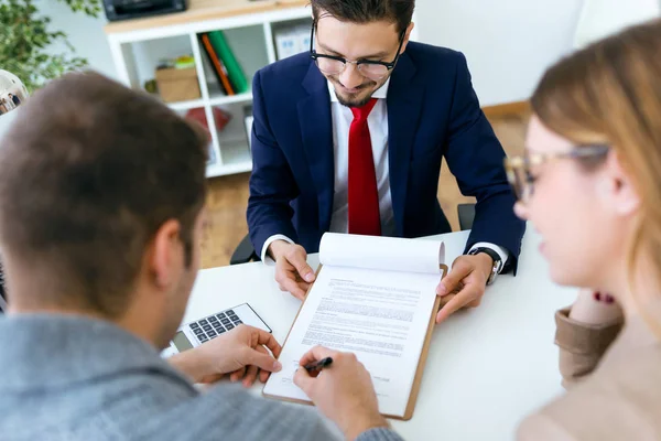 Bonito jovem casal assinar contrato financeiro no escritório . — Fotografia de Stock