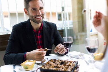 Salyangoz restoranda güzel genç adam yemek konservesi.