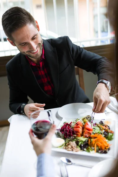 Joven guapo sirviendo ensalada en un plato en el restaurante . — Foto de Stock