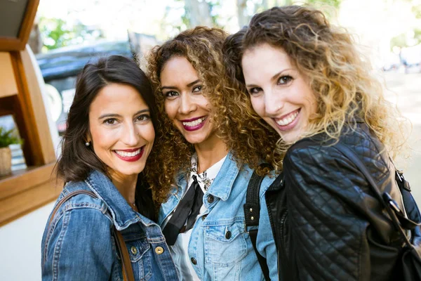Trzy piękne młode kobiety, patrząc na kamery na ulicy. — Zdjęcie stockowe
