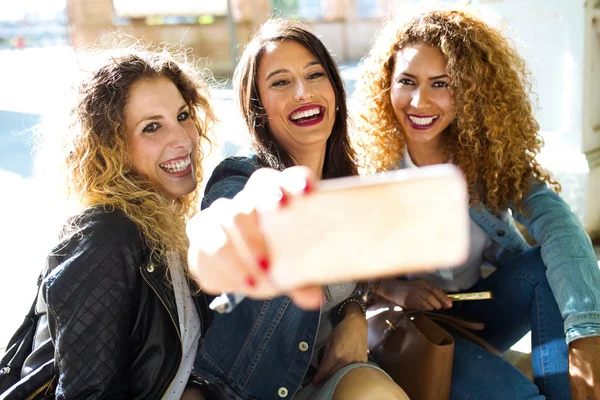 Drie mooie jonge vrouwen met ze mobiele telefoon in de straat. — Stockfoto