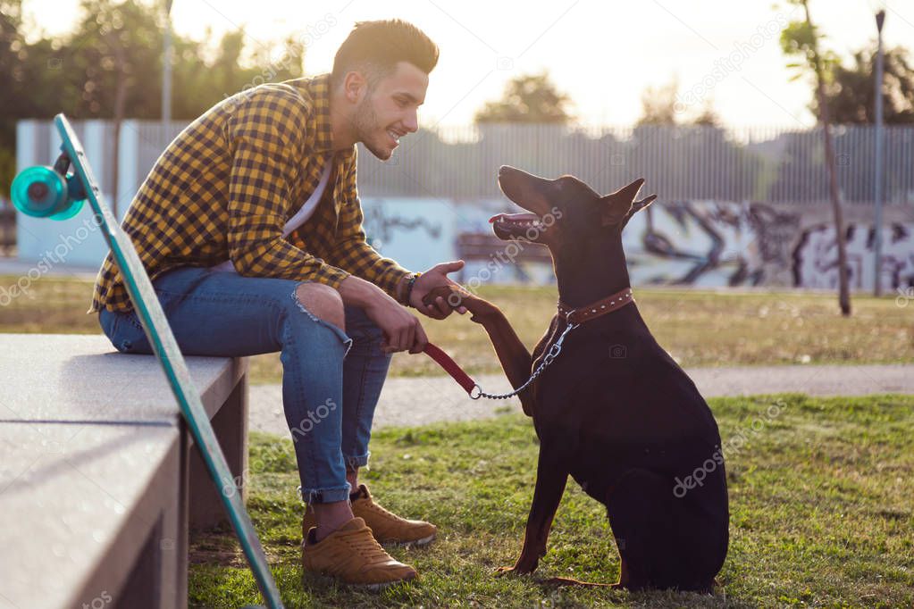 Handsome young man playing with his dog in the park.