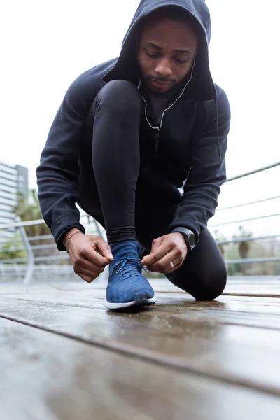Здоровый и спортивный молодой человек, завязывающий шнурки перед пробежкой по городу . — стоковое фото