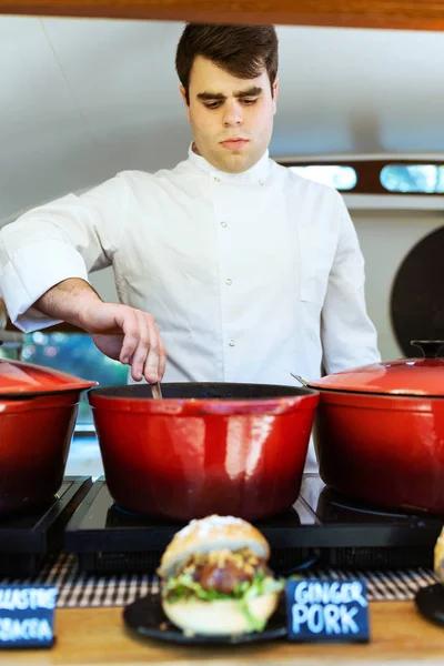 Bonito jovem chef preparando almôndegas em um caminhão de alimentos — Fotografia de Stock
