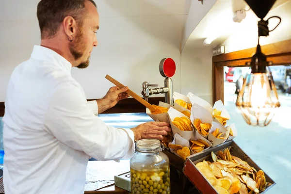 Jonge chef-kok serveert barbecue aardappelen in een food truck. — Stockfoto