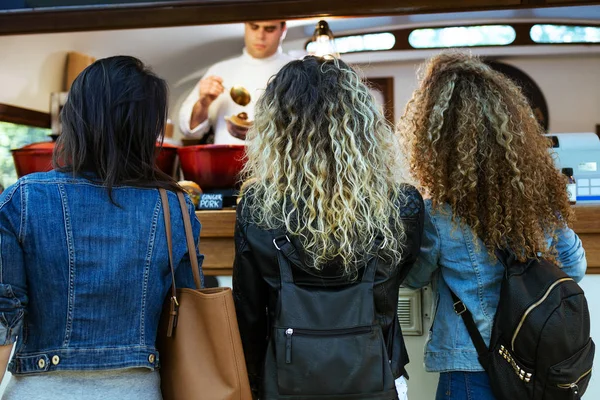 Drei schöne junge Frauen kaufen Frikadellen auf einem Food-Truck. — Stockfoto