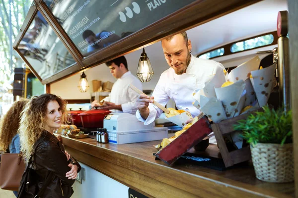 Två vackra unga kvinnor att köpa grill potatis på en foodtruck. — Stockfoto