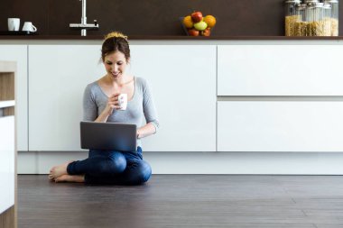 Güzel genç kadın mutfakta evde onun dijital tablet kullanma.