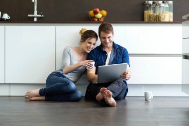 Güzel genç bir çift kullanarak onlar mutfakta dijital tablet 