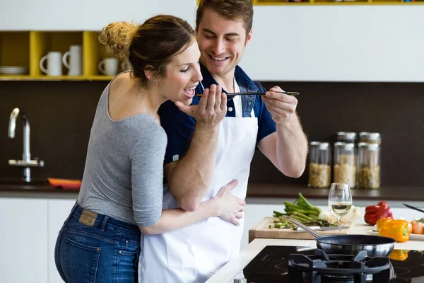 Feliz casal jovem cozinhar juntos na cozinha em casa. — Fotografia de Stock