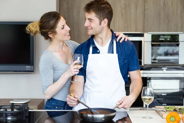 Glückliches junges Paar kocht zu Hause gemeinsam in der Küche. — Stockfoto