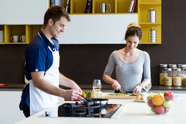 Feliz casal jovem cozinhar juntos na cozinha em casa. — Fotografia de Stock