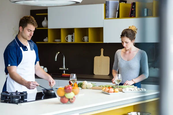 Feliz pareja joven cocinando juntos en la cocina en casa. — Foto de Stock