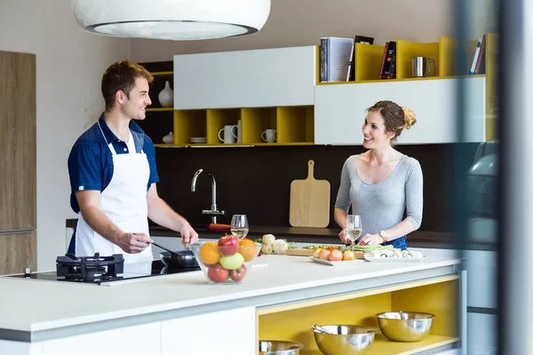 Feliz casal jovem cozinhar juntos na cozinha em casa. — Fotografia de Stock