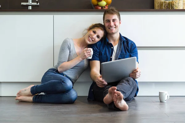 Hermosa pareja joven utilizando la tableta digital en la cocina — Foto de Stock