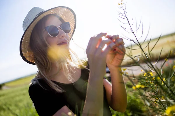 Schöne junge Frau mit Blumen genießt den Sommer auf einem Feld. — Stockfoto