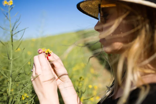 Hermosa joven con flores disfrutando del verano en un campo . — Foto de Stock