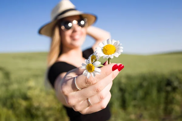 Schöne junge Frau mit Blumen genießt den Sommer auf einem Feld. — Stockfoto