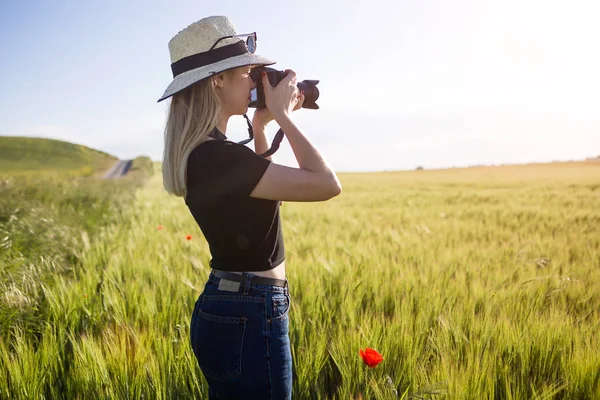 Beautiful young woman with digital camera taking photos in a fie — Stock Photo, Image