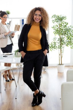 Güzel genç iş kadını ofiste kamera bakıyor.