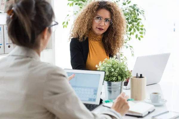 Deux femmes d'affaires travaillant avec un ordinateur portable dans son bureau . — Photo