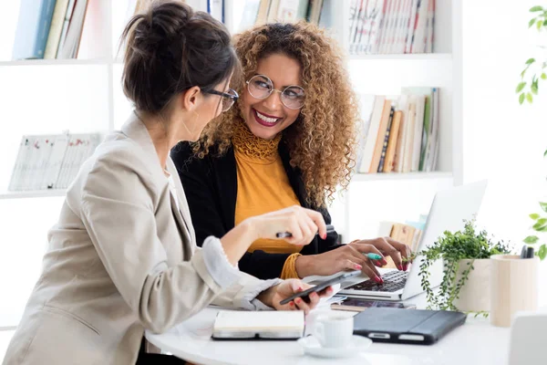 Deux femmes d'affaires travaillant avec un ordinateur portable dans son bureau . — Photo