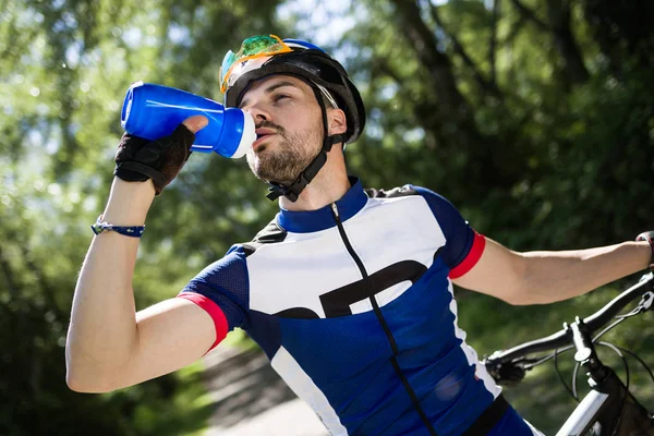 Dağın içinde Bisiklete binme sonra içme suyu yakışıklı genç adam. — Stok fotoğraf