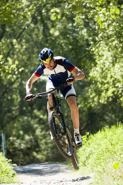 Yakışıklı genç adam dağın içinde Bisiklete binme. — Stok fotoğraf