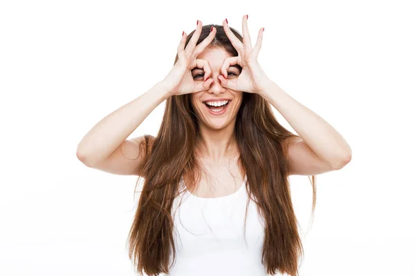 Mulher bonita fazendo óculos de dedo e sorrindo sobre fundo branco . — Fotografia de Stock