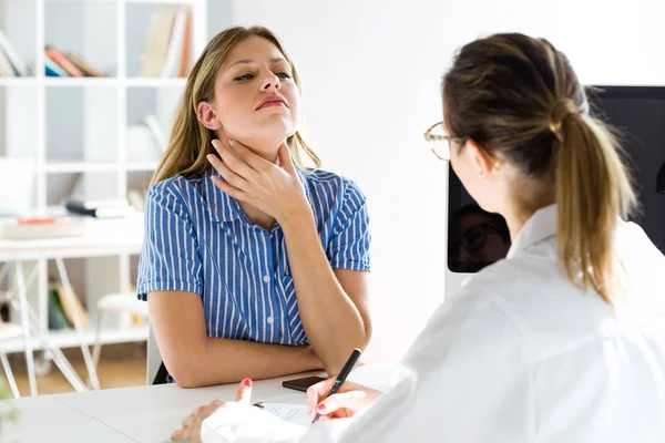 Schöne junge Patientin erklärt der Ärztin ihre Symptome. — Stockfoto