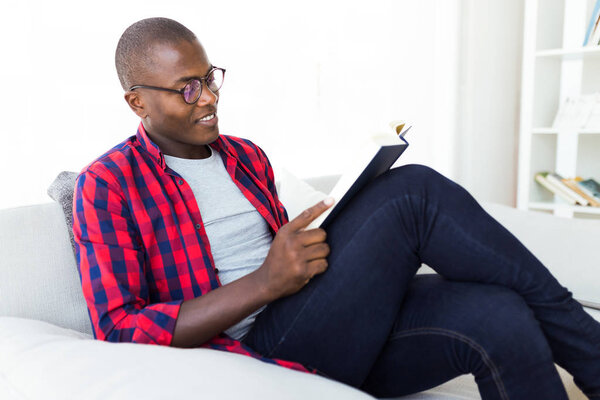 Handsome young man reading a book at home.