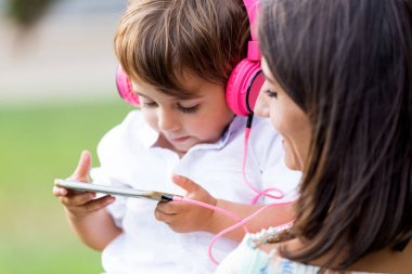 Güzel genç anne oğluyla parkta müzik dinlemek.