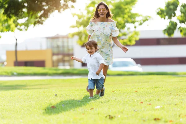 Beautiful young mother with her son having fun in the park. — Stock Photo, Image