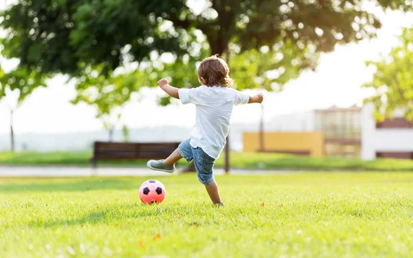 Le petit garçon jouant avec la balle dans le parc . — Photo