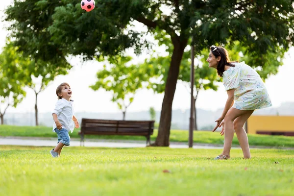 Hermosa madre joven con su hijo divirtiéndose en el parque . — Foto de Stock