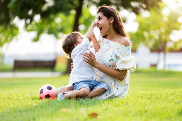 Bela jovem mãe com seu filho se divertindo no parque . — Fotografia de Stock