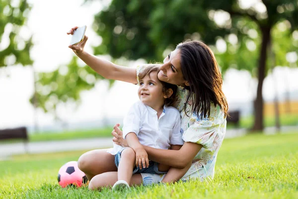 공원에는 selfie를 복용 그녀의 아들과 함께 아름 다운 젊은 어머니. — 스톡 사진
