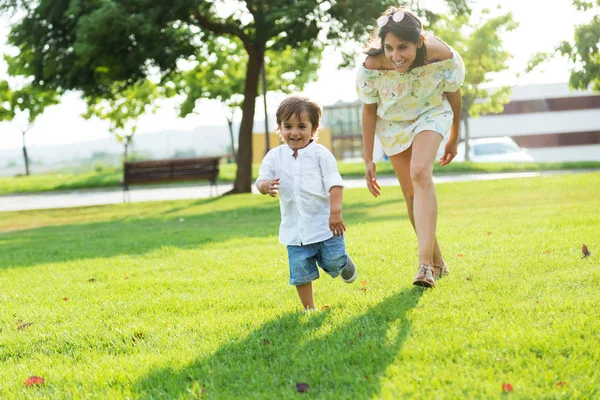 Beautiful young mother with her son having fun in the park. — Stock Photo, Image